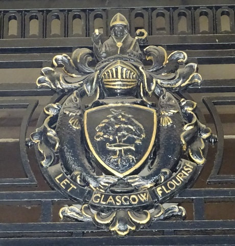 An ornate CoA in black & gold above the entrance to 40 John Street