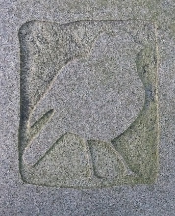 Detail of bird carved in shallow relief on a (possibly granite) stone block.