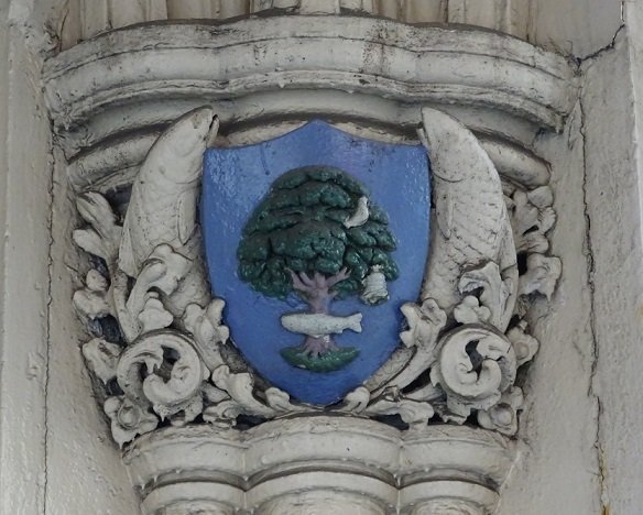 Painted relief of the bird, tree, bell, fish motif within a shield, flanked by salmon, on a pillar below the Tron church tower, Trongate