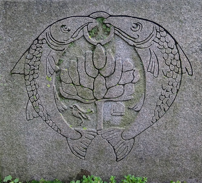 Detail of Glasgow CoA carved in shallow relief on a (possibly granite) stone block. Two large salmon encircle the bird/tree/bell/fish motif, with their heads meeting at the top of the circle as they share the same ring 